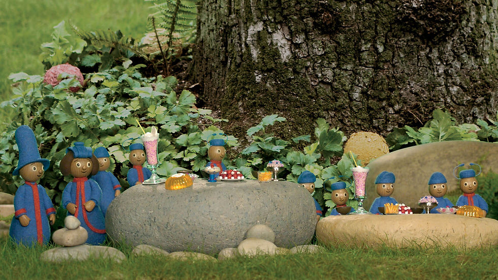 Miniature characters, wearing the same blue uniforms, sitting on large rocks in front of a tall tree.