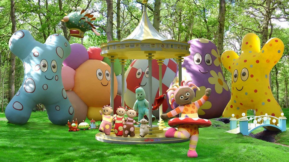 Six character in varios shapes and sizes playing in the middle of a park. Behind them are tall trees and huge, a gazebo and colourful balloons.