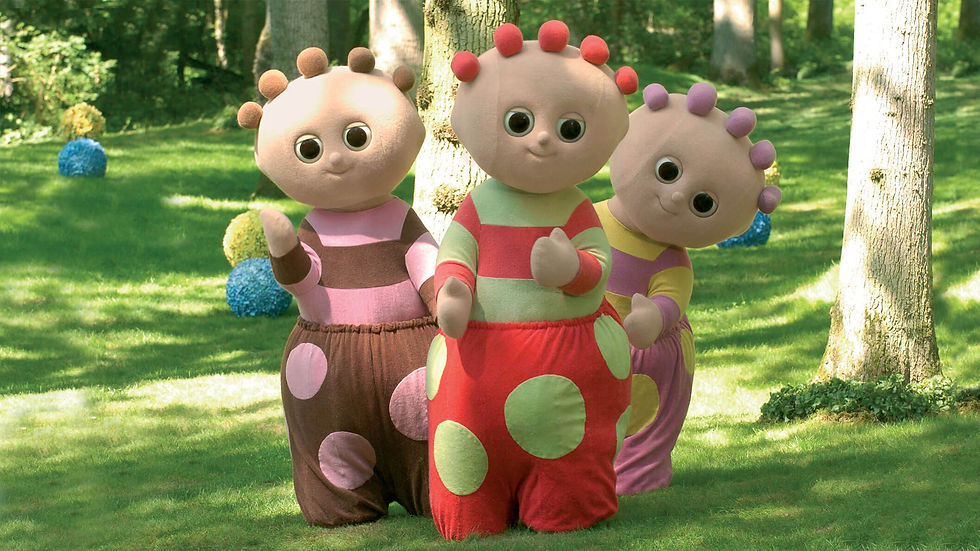 Three characters, in colourful, polka dot costumes, standing beside each other in a green park.