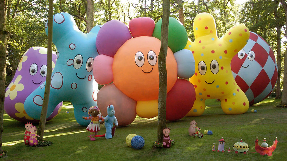 giant colourful characters  with big eyes and smiles looking down on the rest of the characters in the forest