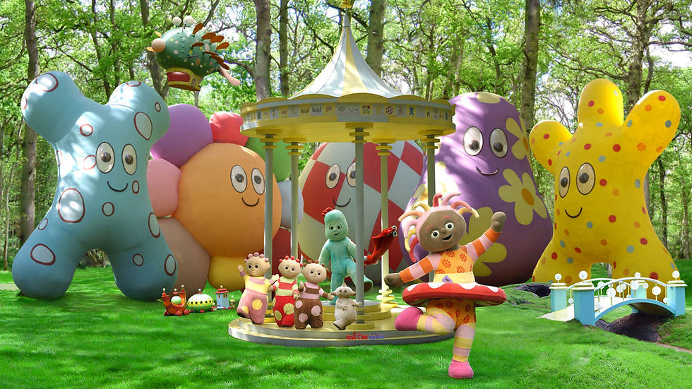 Six character in varios shapes and sizes playing in the middle of a park. Behind them are tall trees and huge, a gazebo and colourful balloons.