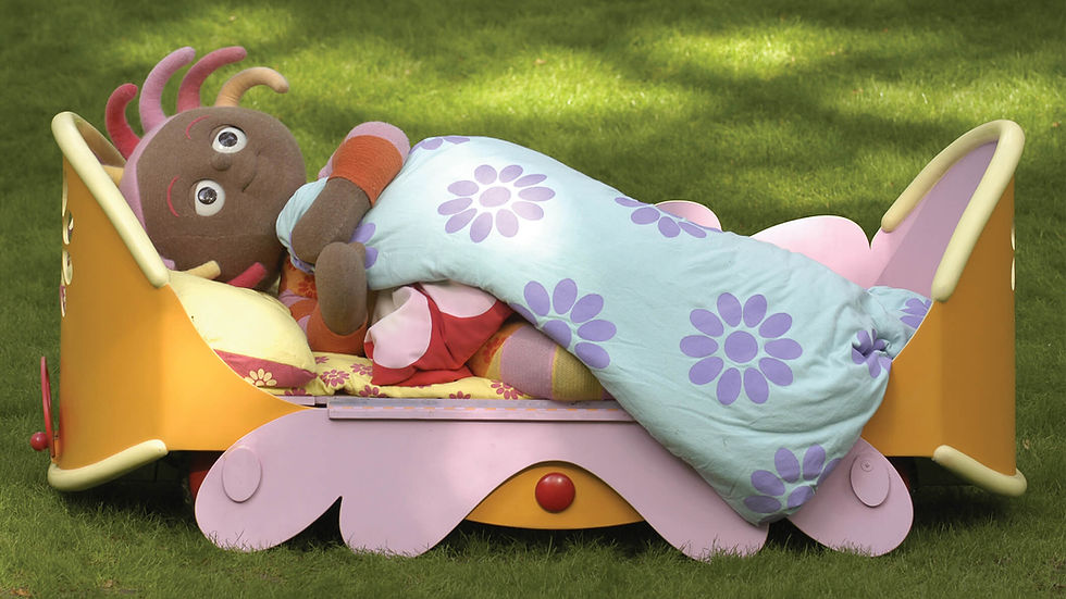 a girl lays in bed covered by a floral blanket in the middle of a forest