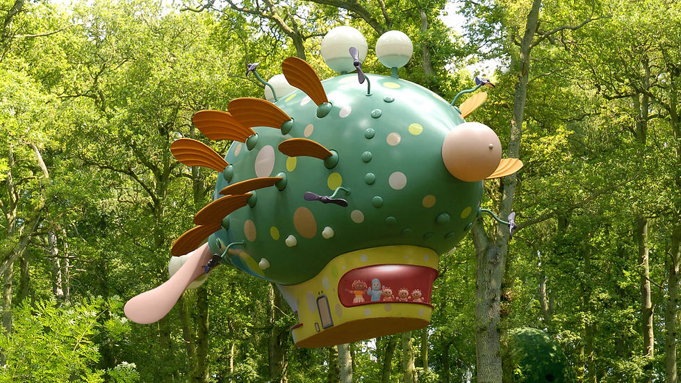 A green, oval shaped spacecraft hovering in a park, in front of green trees.